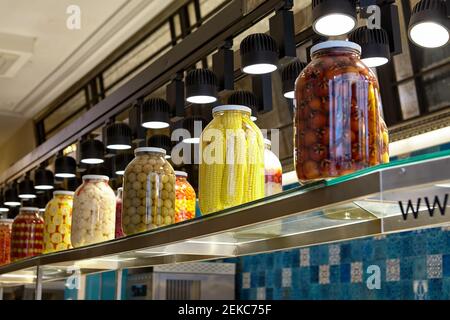 Verzinntes Gemüse und Obst in großen Gläsern auf Lebensmittelgeschäft Regal sind wie hausgemachte Gurken und Marinaden. Stockfoto