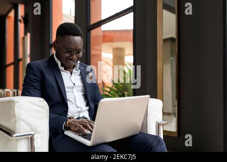 Ein hübscher junger Geschäftsmann, der im Hotel sitzt und am Laptop arbeitet Lobby Stockfoto