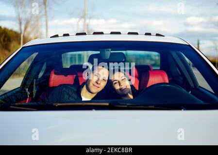 Junges Paar lächelt, während sie im Auto sitzt Stockfoto