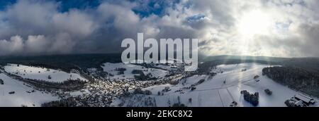 Deutschland, Bayern, Mespelbrunn, Helikopterpanorama der Sonne, die die schneebedeckte Stadt im Spessart Range erleuchtet Stockfoto