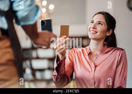 Glückliche weibliche Kundin, die mit Kreditkarte an den männlichen Kellner zahlte Im Café Stockfoto