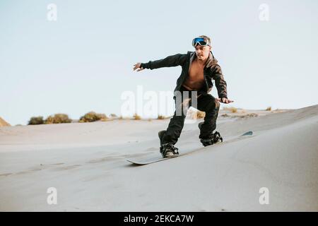 Junger Mann sand surfing auf Sanddünen gegen klaren Himmel in Almeria, Wüste Tabernas, Spanien Stockfoto