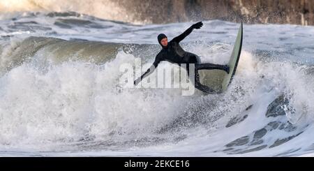 Mann für mittlere Erwachsene, der auf dem Meer am Broad Haven South Beach, Pembrokeshire, Großbritannien surft Stockfoto