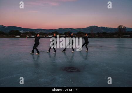 Weibliche Eiskunstläuferinnen üben auf gefrorenem See in der Dämmerung Stockfoto