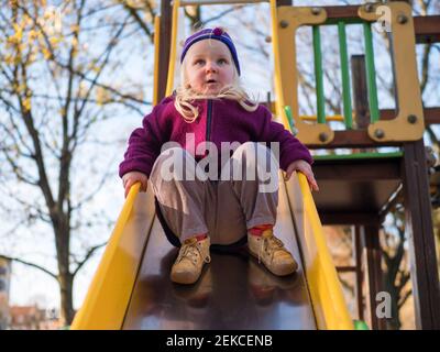 Süße Mädchen spielen auf Folie am Spielplatz Stockfoto