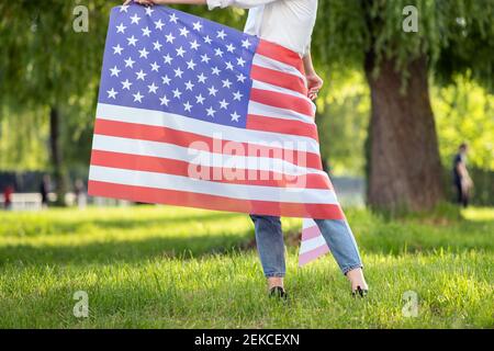 Frau mit US-Nationalflagge um ihre Taille steht im Sommer Park im Freien. Stockfoto