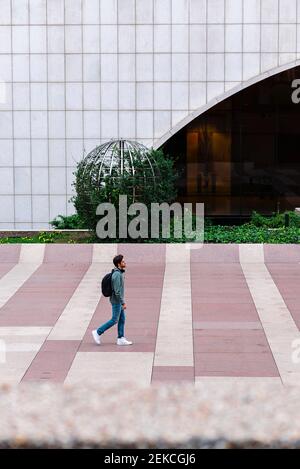 Einsamer männlicher Student mit Rucksack zu Fuß auf dem Universitätscampus Stockfoto