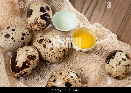 Zusammensetzung von mehreren Wachteleiern auf dekorativem Stoff auf einem Holztisch Nahaufnahme, Flatlay Stockfoto