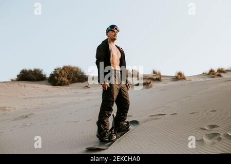 Junger Mann mit Sandbrett, während er auf Sand in Almeria, Wüste Tabernas, Spanien steht Stockfoto