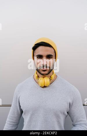 Schöner junger Mann mit gelben Kopfhörern an der grauen Wand Stockfoto