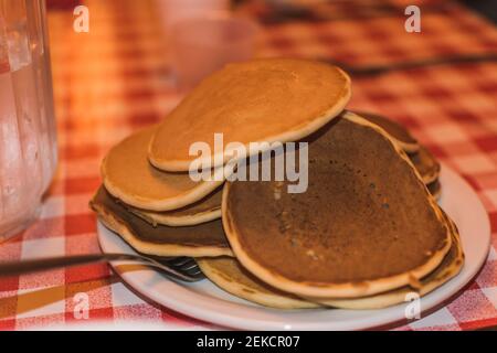 Pfannkuchen auf einem Teller auf einem rot und weiß gestapelt Karierte Tischdecke Stockfoto
