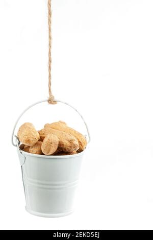 Ein voller Eimer Erdnüsse, der an einem Seil hängt. Weißer Hintergrund Stockfoto