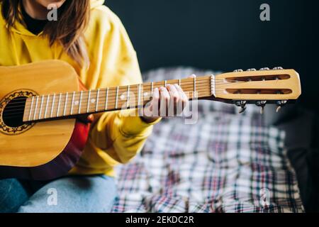 Nahaufnahme die Hand einer jungen Frau, die zu Hause akustische Gitarre spielt. Stockfoto