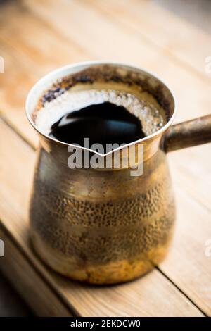 Kaffeekocher mit heißem Kaffee auf dem Holztisch. Selektiver Fokus. Geringe Schärfentiefe. Stockfoto
