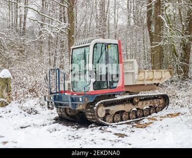 Kleiner Raupenwagen mit Muddy-Chassis. Der Transporter wartet im verschneiten Wald Stockfoto