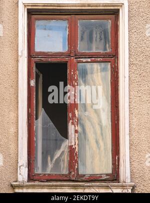 Geschlossenes, gebrochenes Holzfenster eines alten Gebäudes. Stockfoto