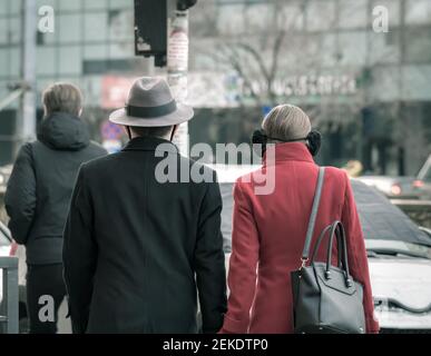 Rückansicht eines jungen, modernen Paares, das Hände hält und im geschäftigen Zentrum von Bukarest, Rumänien, läuft. Stockfoto
