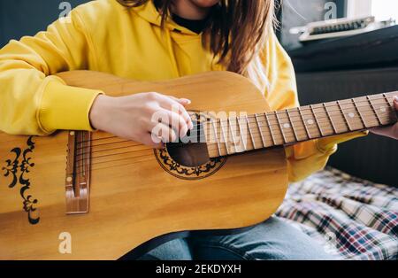 Nahaufnahme die Hand einer jungen Frau, die zu Hause akustische Gitarre spielt. Stockfoto