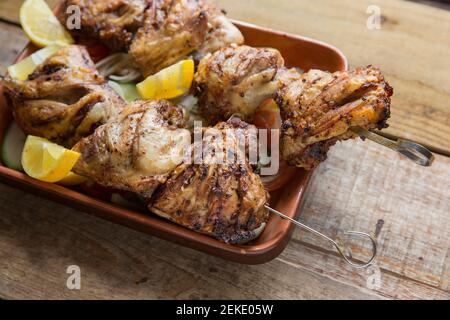 Britische Hähnchenschenkel, die in Öl, Chili-Flocken und Ruck gewürzt wurden mariniert, bevor sie spieß und gegrillt. Serviert mit Gurke, Zwiebel Stockfoto