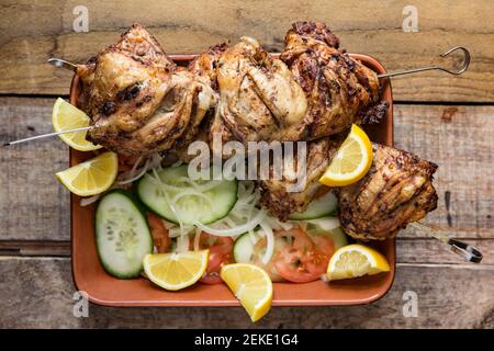 Britische Hähnchenschenkel, die in Öl, Chili-Flocken und Ruck gewürzt wurden mariniert, bevor sie spieß und gegrillt. Serviert mit Gurke, Zwiebel Stockfoto