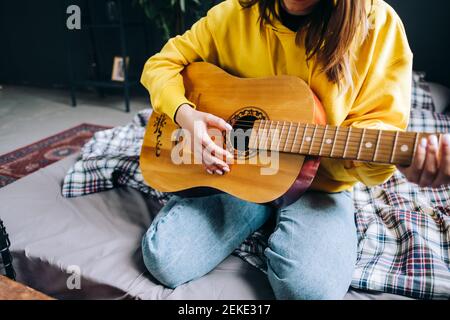 Nahaufnahme die Hand einer jungen Frau, die zu Hause akustische Gitarre spielt. Stockfoto