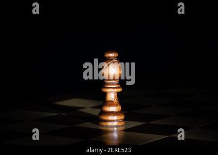 Schachfigur aus dunklem Holz an Bord mit schwarzem Hintergrund. Stockfoto