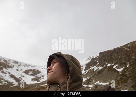 Stock Foto von einem Mann in Tarnkleidung, und Trekking in den hohen Berg von Moncayo in Aragon, Spanien, umgeben von riesigen felsigen und schneebedeckten Hi Stockfoto