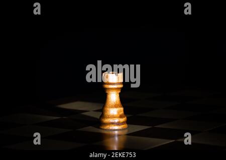 Schachfigur aus dunklem Holz an Bord mit schwarzem Hintergrund. Stockfoto