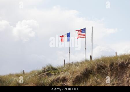 Die französischen und amerikanischen Flaggen wehen im Wind über den Dünen von Utah Beach. Normandie, Frankreich Stockfoto