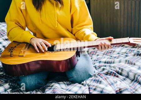 Nahaufnahme die Hand einer jungen Frau, die zu Hause akustische Gitarre spielt. Stockfoto