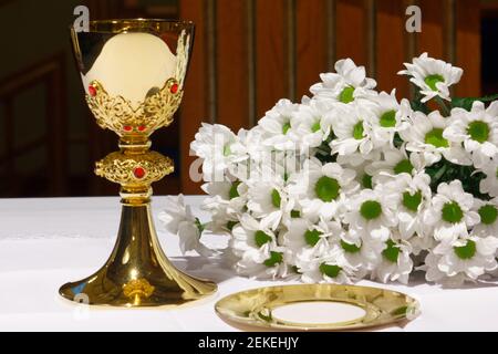 Ein goldener Kelch mit weißen Blumen und bibel. Religion. Christentum. Heilige Kommunion. Katholisches Thema. Stockfoto