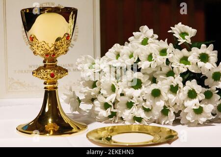 Ein goldener Kelch mit weißen Blumen und bibel. Religion. Christentum. Heilige Kommunion. Katholisches Thema. Stockfoto