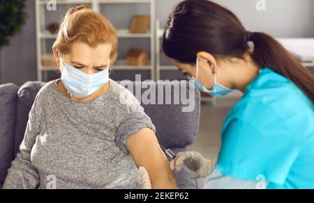 Leitender Patient mit Gesichtsmaske, der Grippe oder Covid-19-Impfstoff erhält Injektion in ihren Arm Stockfoto