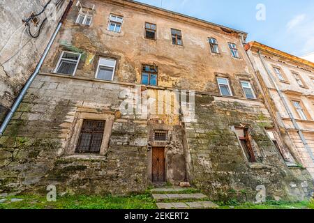 Lviv Ukraine alt heruntergekommenes verfallenes Appartementhaus mit verlassenen Fenstern Architektur im Sommer und schälende Wand Weitwinkel Blick außen Stockfoto