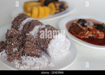 Gedämpfte Fingerhirse und Kokosnusskuchen, serviert mit Sardinen-Curry und gedämpfter Kochbanane. Schuss auf weißem Untergrund Stockfoto