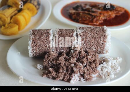 Gedämpfte Fingerhirse und Kokosnusskuchen, serviert mit Sardinen-Curry und gedämpfter Kochbanane. Schuss auf weißem Untergrund Stockfoto