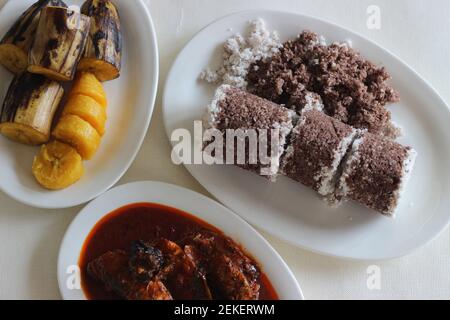 Gedämpfte Fingerhirse und Kokosnusskuchen, serviert mit Sardinen-Curry und gedämpfter Kochbanane. Schuss auf weißem Untergrund Stockfoto