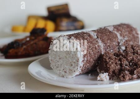 Gedämpfte Fingerhirse und Kokosnusskuchen, serviert mit Sardinen-Curry und gedämpfter Kochbanane. Schuss auf weißem Untergrund Stockfoto