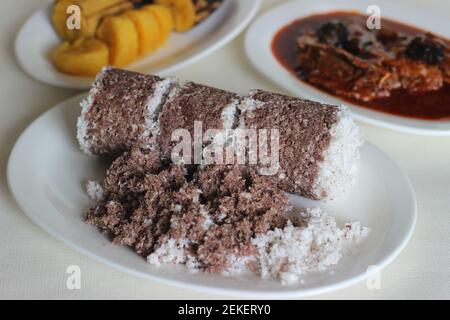 Gedämpfte Fingerhirse und Kokosnusskuchen, serviert mit Sardinen-Curry und gedämpfter Kochbanane. Schuss auf weißem Untergrund Stockfoto