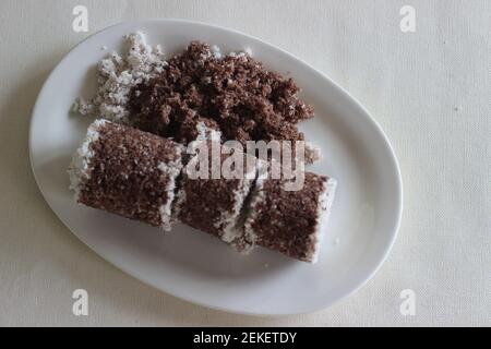 Gedämpfter Hirsekuchen. Hergestellt mit Fingerhirse Mehl kombiniert mit geriebenem Cocunut und in einem speziellen Behälter gedämpft. Es wird auch Ragi Putt genannt Stockfoto