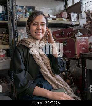 Junge iranische Dame in einem traditionellen Kleid mit einem Kopftuch sitzt im Lebensmittelgeschäft. Shiraz, Iran. Stockfoto