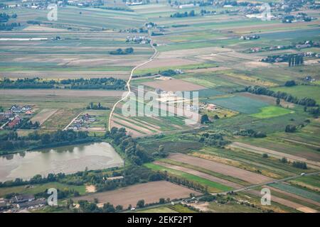 Nowy Dwor, Polen über Luftaufnahme vom Flugzeugfenster in der Nähe des Flughafens mit ländlicher grün-brauner Landschaft in der Nähe von Warschau und Bauernhöfen Stockfoto