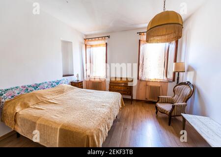 Rustikales altmodisches italienisches Landhaus oder Haus Cottage Schlafzimmer in villa mit Queen-Size-Bett und Holzboden mit Fenstern Stockfoto