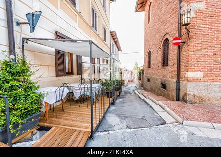 Chiusi, Italien - 25. August 2018: Schmale Gasse Straße mit Restaurant Tische Terrasse in kleinen Dorf in der Toskana und niemand Stockfoto