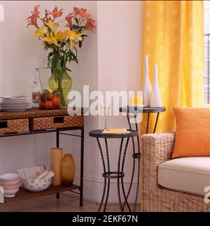 Runde Tische vor dem Weidensofa und Wicket und Beistelltisch aus Metall mit großer Vase in Orange und Gelb Farbl Stockfoto