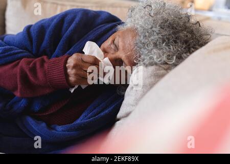 Kranke afroamerikanische ältere Frau, die auf der Couch liegt Stockfoto