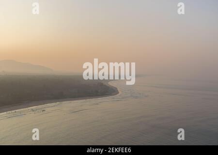 Luftpanorama des schönen Murdeshwar Strand und Arabian Sea auf einem nebligen Wintermorgen mit orange und gelb Schattierungen im Himmel bei Murdeshwar, Stockfoto