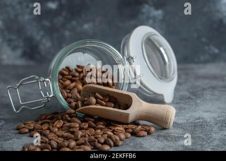 Ein Glas mit einem Holzlöffel voll Kaffee Bohnen Stockfoto