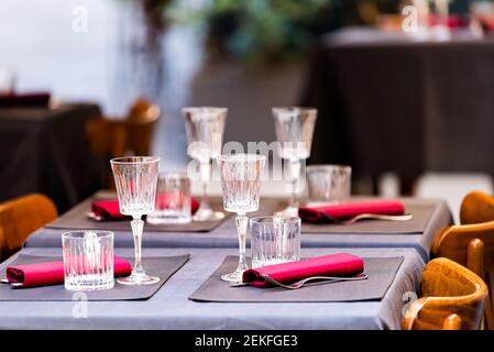 Nahaufnahme von vier Gläsern auf leerem Restauranttisch in Italien, italienisches Cafe draußen mit roten und blauen lila rosa Farben und niemand Stockfoto