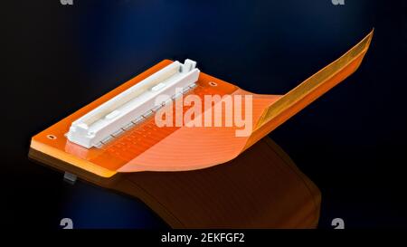 Orangefarbene Flex-Platine mit weißem Steckverbinder und Reflektion auf schwarzem Hintergrund. Künstlerische Stillleben mit gebogenen Kunststoff PCB Detail. Elektronisches Gerät. Stockfoto